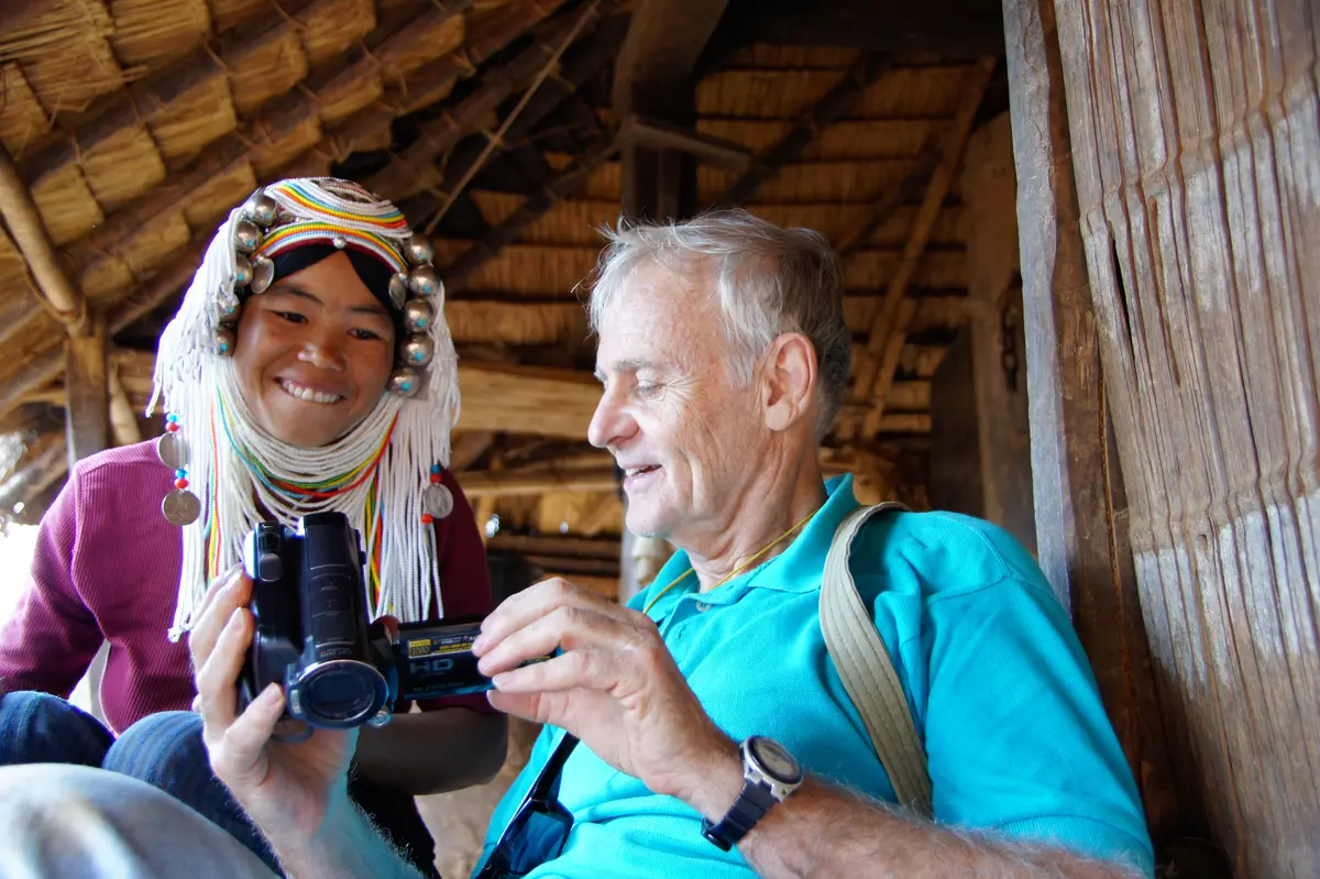 Robert H. Lieberman showing video camera footage to a smiling woman in a traditional beaded headdress